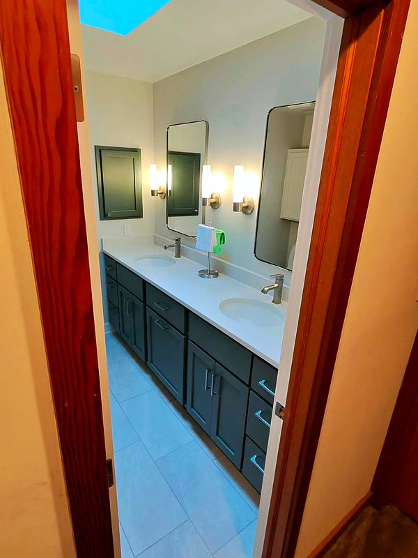 After: dark double vanity with quartz top and large-format tile floor